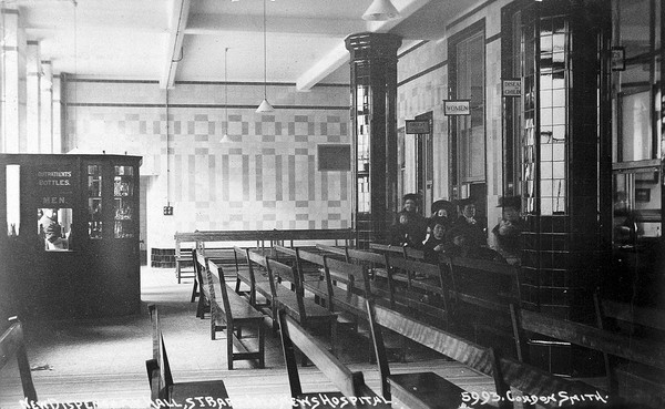 St Bartholomew's Hospital, London: patients queuing for prescriptions in the dispensary hall. Photograph, c. 1908.