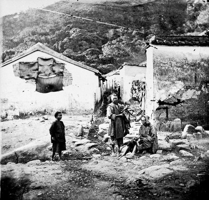 Native houses, with two women and a child in the foreground, Swatow, Kwangtung Province, China.