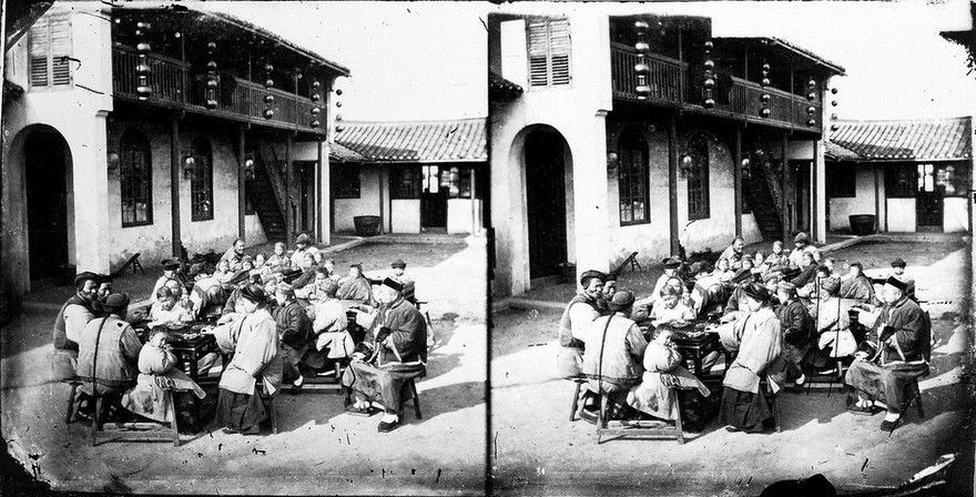 A Peking mission-school with children and teachers sitting around tables, eating, in a courtyard, Peking, Pechili Province. China