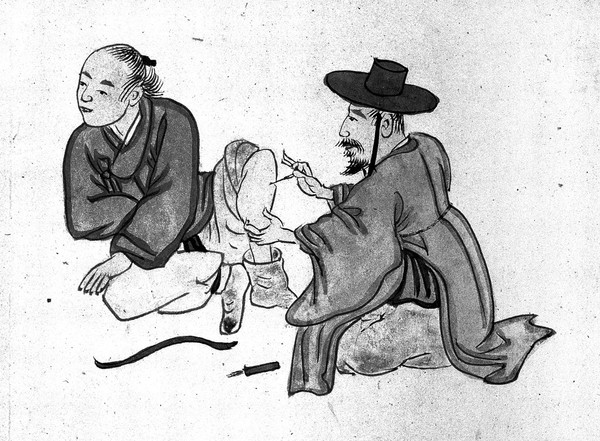 A Korean acupuncturist inserting a needle into the leg of a male patient.