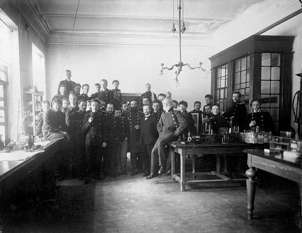 Interior of a physiology laboratory either at the Institute of Experimental Medicine or at the Imperial Military Medical Academy, St Petersburg, with I.P. Pavlov seated on a workbench and other people behind. Photograph, 1904.