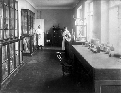 A physiology laboratory, either at the Institute of Experimental Medicine or at the Imperial Military Medical Academy, St Petersburg, with workbenches, cabinets of apparatus, and two members of staff. Photograph, 1904.