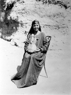 Bani Suef, Egypt: a midife holding a kulleh (pottery water jar) at the naming ceremony of a baby. Photograph by W.S. Blackman, 192-.