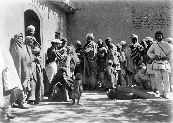 Dr Hamilton examining a child's eyes outside the surgery surrounded by waiting people.