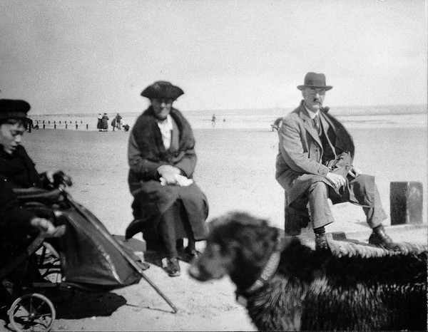 A physically disabled boy sitting in a wheelchair on a beach. Photograph, ca. 1910/1925.