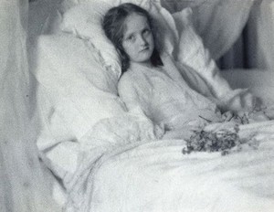 view A convalescent girl, lying in bed, holding a bunch of flowers. Photograph by Ernest G. Boon, ca. 1904.