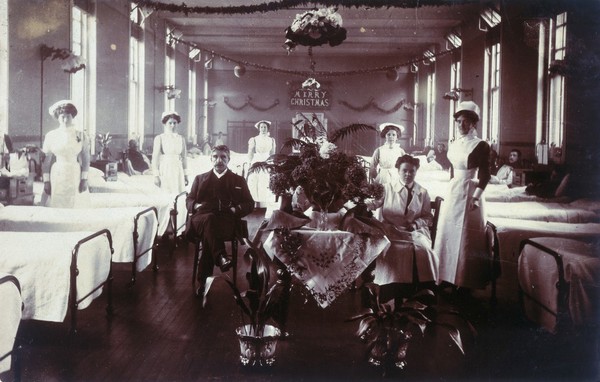 A hospital ward with Christmas decorations. Photographic postcard.