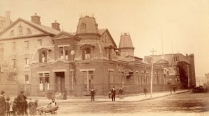 view Bellevue Hospital, New York City: a street corner with hospital buildings and people. Photograph.