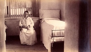 view Bellevue Hospital, New York City: a female patient (criminal insane?) in a cell with barred windows. Photograph.