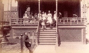 view Bellevue Hospital, New York City: children patients, nurses and doctors sitting on a balcony in the sunshine. Photograph.
