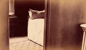 view Bellevue Hospital, New York City: a cell with bed seen through doorway. Photograph.