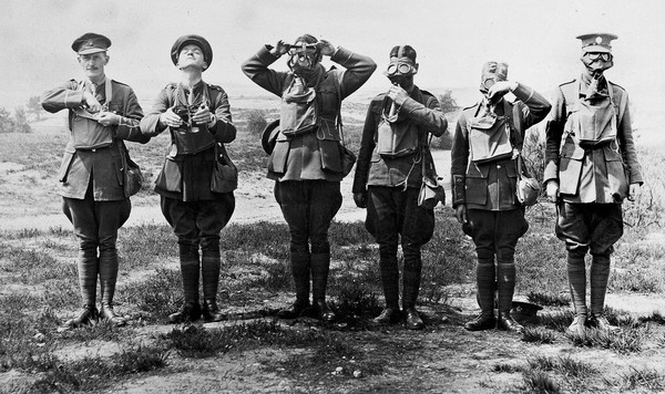 Six soldiers demonstrating putting a gas mask on over the face. "To show stages in adjustment of a SBR".