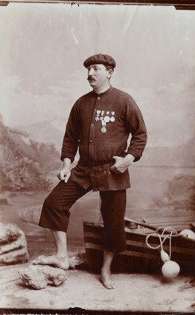 A barefoot Basque fisherman posing with several medals on his tunic.