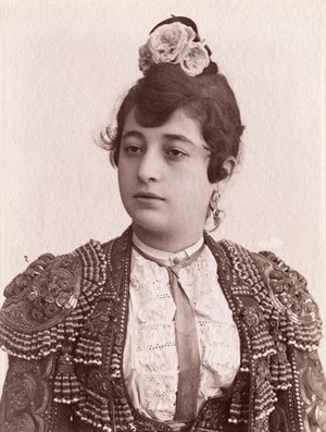 view A female bullfighter, with flowers in her hair, wearing a matador's jacket. Photograph by Castillo, ca. 1900.