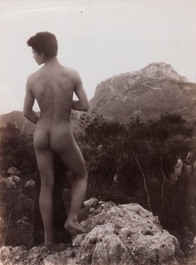 A naked Sicilian boy, in a rocky setting outdoors. Photograph, 1900, by W. von Gloeden.