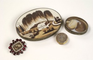 view Mourning brooches containing the hair of a deceased relative.