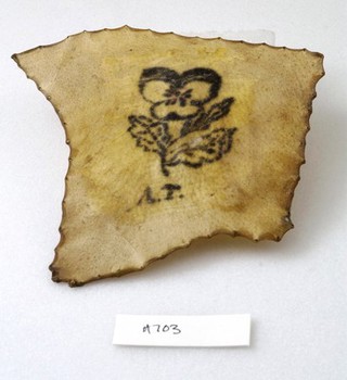 A tattoo on a piece of human skin showing a flower and some initials