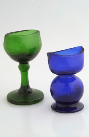 view Two coloured glass eye baths in blue and green.