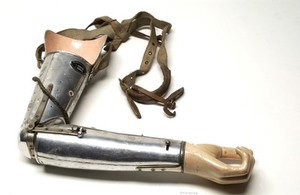 view Artificial left arm, metal, with hand and canvas shoulder strap. Made by the Mckay Artificial Limb Company.