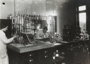 view Chemical research lab, Beckenham. Two chemists at work, surrounded by equipment and apparatus.