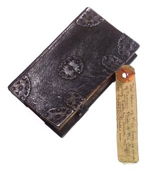 view A notebook allegedly covered in human skin. The label reads 'The cover of this book is made of Tanned Skin from the Negro whose Execution caused the War of Independence'. c. 1770 - 1850