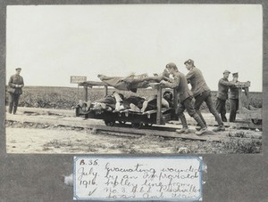 view World War One: moving wounded men on a trolley on rails at Puchevillers, France. Photograph, 1916.