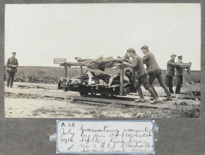 World War One: moving wounded men on a trolley on rails at Puchevillers, France. Photograph, 1916.