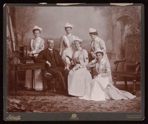 A doctor with five nurses: studio portrait. Photograph, ca. 1900.
