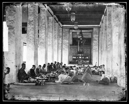 Buddhist monks receiving lunch at Sutthai Sawan Throne Hall, Bangkok. Photograph by John Thomson, 1865.