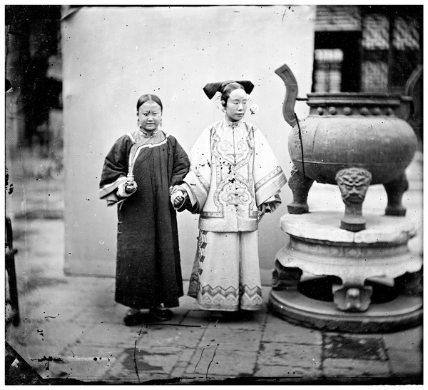 China: a Manchu woman with her maid standing beside a bronze burner, Beijing. Photograph by John Thomson, 1869.
