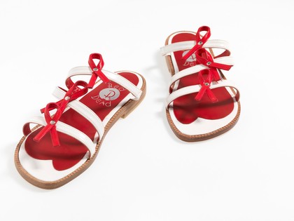 Sandals made of red and white straps incorporating the red ribbon device associated with AIDS. Pair of sandals, 1994.