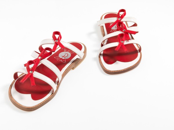 Sandals made of red and white straps incorporating the red ribbon device associated with AIDS. Pair of sandals, 1994.