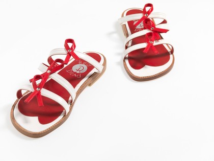 Sandals made of red and white straps incorporating the red ribbon device associated with AIDS. Pair of sandals, 1994.