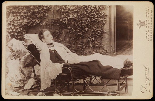 An invalid lady reclining outdoors on a chaise longue. Photograph by J.A. Draycott, 189-.