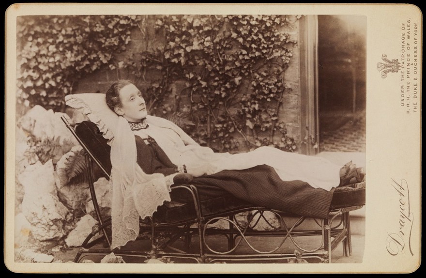 An invalid lady reclining outdoors on a chaise longue. Photograph by J.A. Draycott, 189-.