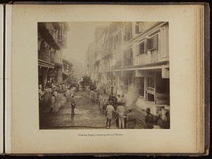 view Groups of men on a street spraying jets of water into plague infected houses, during the epidemic of plague in Bombay. Photograph attributed to Captain C. Moss, 1897.