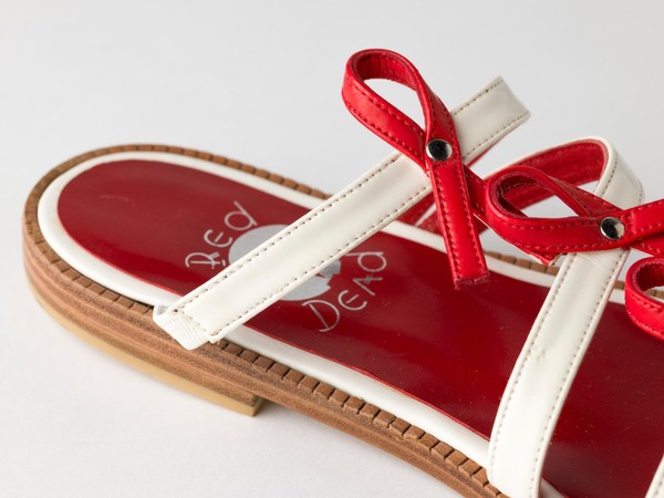 Sandals made of red and white straps incorporating the red ribbon device associated with AIDS. Pair of sandals, 1994.
