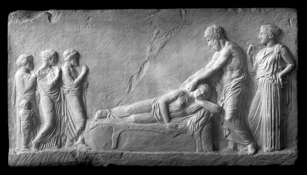 Fragment of bas-relief in the from of a temple. A girl patient on a bed, Aesculapius stands above her. Bas-relief, plaster cast from the original in Athens. Greece