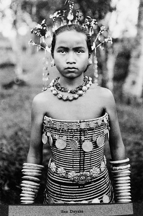 Sea Dayaks, female figure wearing spiral corsets decorated with medals