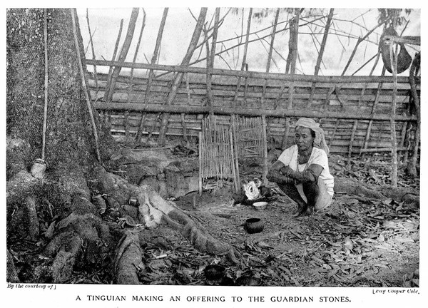 A Tinguian making an offering to the guardian stones. The stones, in which the guardian spirits are supposed to live, are, before certain ceremonies, tied up with bark-like bands and rubbed with oil. Then the blood for a pig is mixed with rice which is scattered before them.