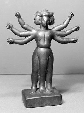 Brass figure of Jvara with three heads and legs and six arms. Jvara is said to be the god of malarial fever. Probably a Hindu village deity.