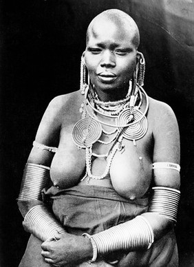 East Africa: a Masai woman wearing heavy armlets, ear-lobe distenders, necklets etc. Process print, 190-.