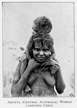 M0013691: A woman carrying a child on her shoulders, Central Australia