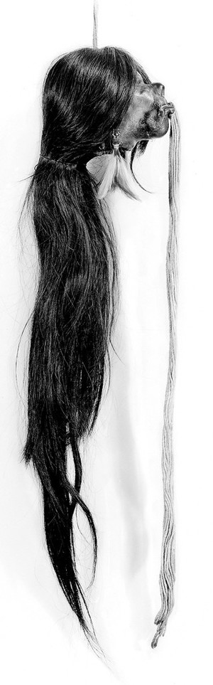view A shrunken head, Jivaro Indian, Ecuador, S.America. Long hair, threads from lips, feather pendant from ears