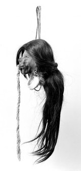 A shrunken head, Jivaro Indian, Ecuador, S.America. Long hair, threads from lips, feather pendant from ears