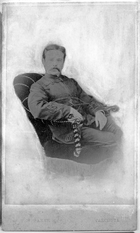 Photographic portrait of T.E. Lewis seated in an arm chair.