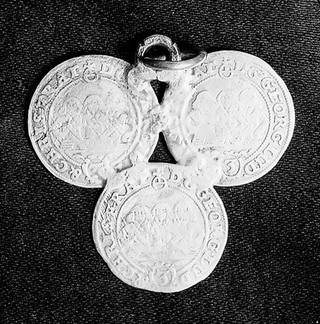 3 identical silver coins joined to form triangle. On one side are three little men.