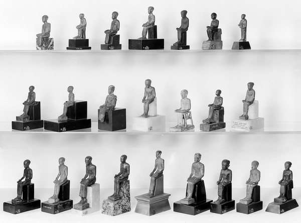 Collection of figures of Imhotep, Egyptian. Group II, front view. L. to R. R50, 39, 69, 37, 75, 78, 59, 58, 38/1936. middle row R34, 62/1936, A63436, 49/1936, MacG. 1264, 80, 54/1936. bottom row R2949, 36, 71, 70, 72, 60, 66/1936