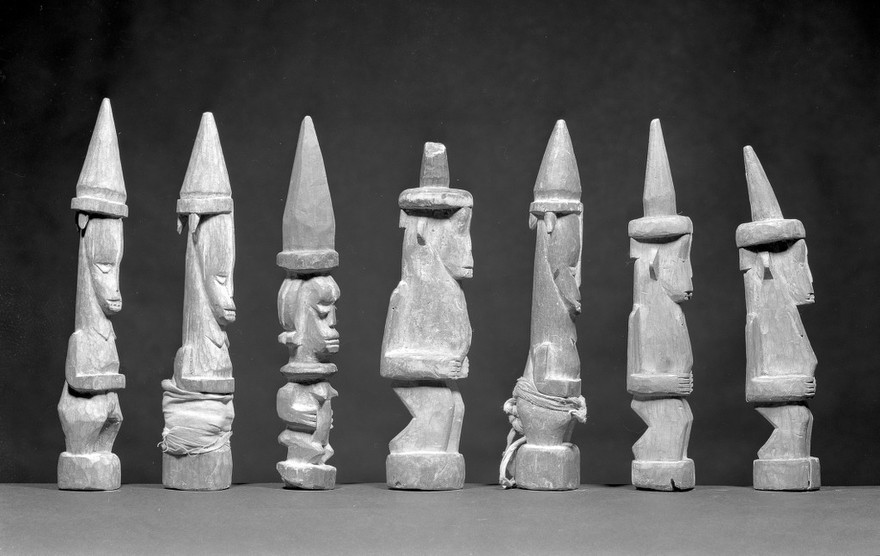 M0019325EB: Seven carved wood statues representing Oma, a household god: side view