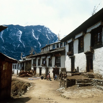 Nepal; town life in the Khumbu, 1986. A street in Namche Bazar (altitude 3446 metres). Men relax outside a store. In the mid-1980s, Nepal was rigidly patriarchical although Sherpa women had more autonomy than other groups. Women generally had limited access to markets, education, health care and local government. Malnutrition and poverty hit them the hardest, and female children were usually given less food than male children, especially during food shortages.